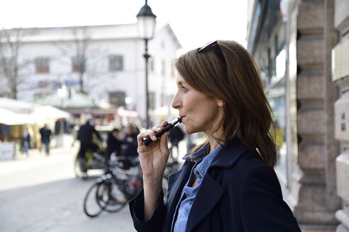 Reife Frau raucht elektronische Zigarette in der Stadt - ECPF00684