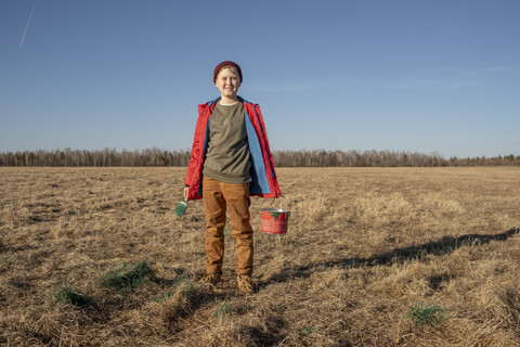 Porträt eines lächelnden Jungen mit Farbeimer und Pinsel in einer Steppenlandschaft, lizenzfreies Stockfoto