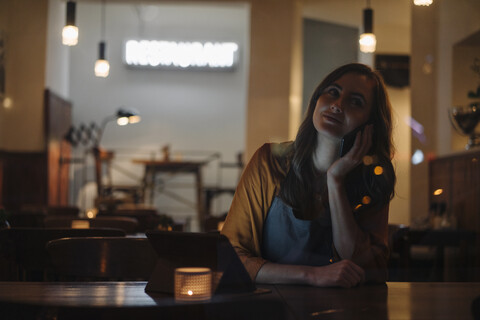 Young woman sitting at table in a restaurant with cell phone and tablet stock photo