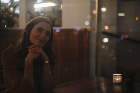 Porträt einer lächelnden jungen Frau hinter einer Fensterscheibe in einem Restaurant, lizenzfreies Stockfoto