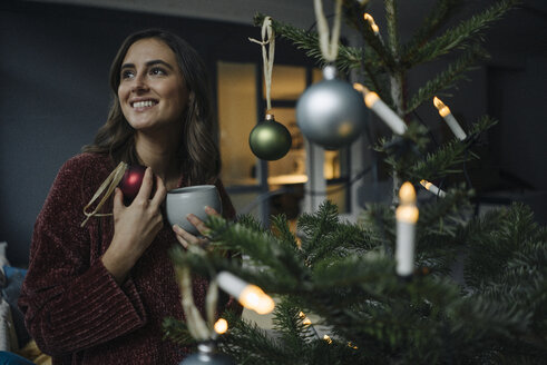 Lächelnde junge Frau beim Schmücken des Weihnachtsbaums - KNSF05806