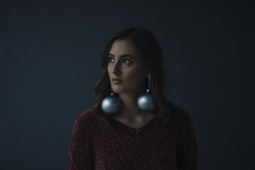 Porträt einer jungen Frau, die Weihnachtskugeln als Ohrringe trägt - KNSF05809