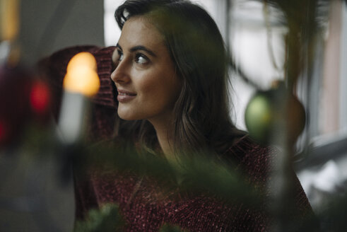 Junge Frau am geschmückten Weihnachtsbaum schaut weg - KNSF05811
