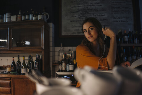 Porträt einer jungen Frau mit Buch an einem Restauranttisch, lizenzfreies Stockfoto