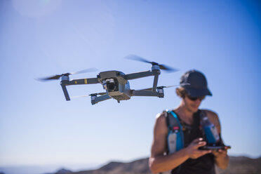 Mann bedient Drohne (unbemanntes Luftfahrzeug) vor blauem Himmel, Nelson, Nevada, USA - ISF21253