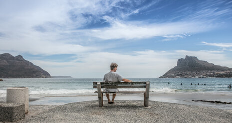 Älterer Mann sitzt und schaut von einer Strandbank aus, Kapstadt, Westkap, Südafrika - ISF21272
