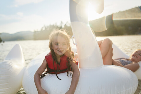 Mädchen spielen auf einem aufblasbaren Schwan im See, lizenzfreies Stockfoto