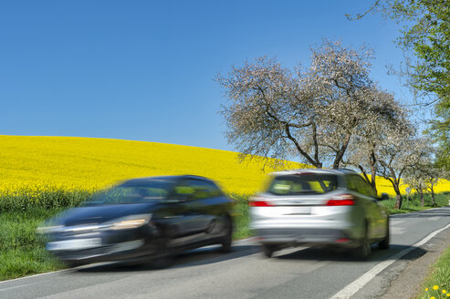 Germany, Mecklenburg-Western Pomerania, two cars passing by on country road - FRF00825