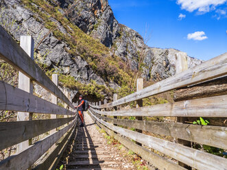 Spain, Asturia, Cantabrian Mountains, senior man on a hiking trip standing on a bridge - LAF02309