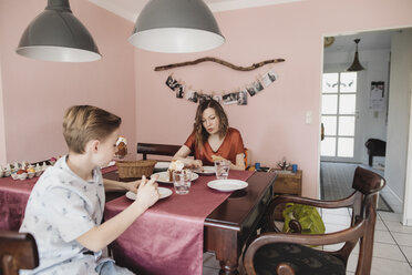 Mother and son sitting at dining table at home - KMKF00934