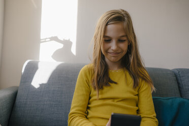 Mädchen auf der Couch zu Hause mit Mobiltelefon - KNSF05830