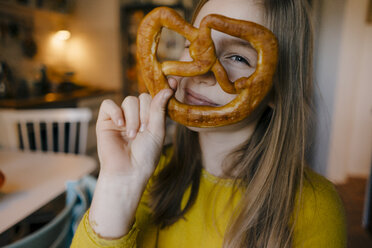 Girl in kitchen holding pretzel - KNSF05834