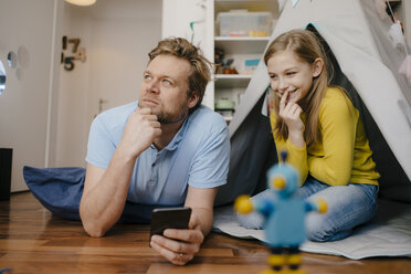 Vater und Tochter mit Mobiltelefon im Kinderzimmer - KNSF05845