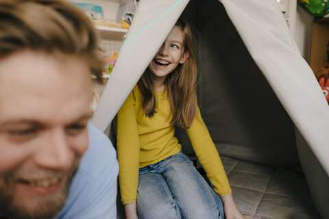 Glücklicher Vater und Tochter mit Tipi im Kinderzimmer, lizenzfreies Stockfoto