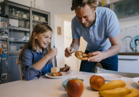 Glücklicher Vater und Tochter zu Hause, die sich am Frühstückstisch amüsieren - KNSF05848