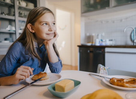 Lächelndes Mädchen zu Hause am Frühstückstisch sitzend - KNSF05849