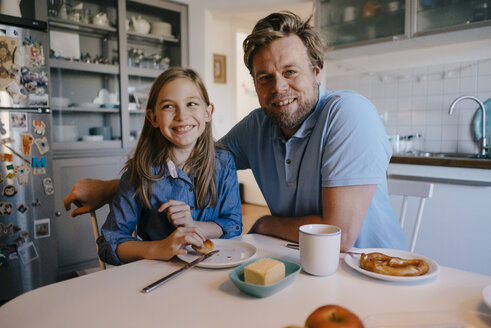 Porträt von Vater und Tochter zu Hause am Frühstückstisch sitzend - KNSF05850