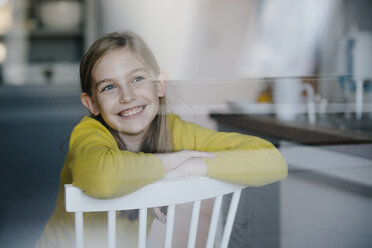 Portrait of a happy girl sitting on chair at home - KNSF05864