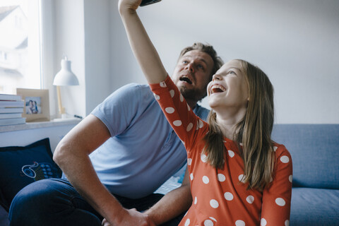 Glücklicher Vater und Tochter machen ein Selfie zu Hause, lizenzfreies Stockfoto