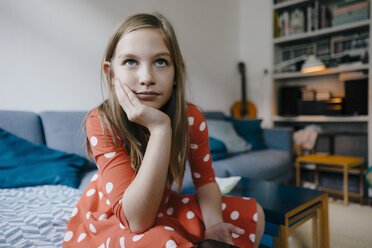 Portrait of serious girl sitting on couch at home - KNSF05875