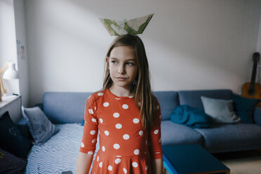 Girl balancing paper boat on her head at home - KNSF05877