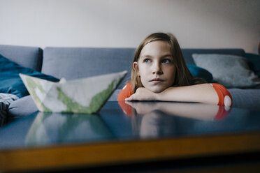 Serious girl resting her head on coffee table at home - KNSF05878