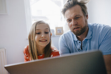 Vater und Tochter benutzen Laptop zu Hause - KNSF05883