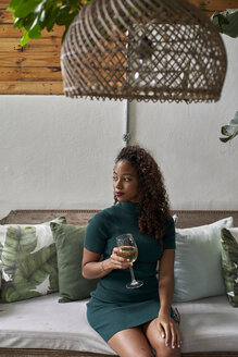 Junge Frau entspannt sich mit einem Glas Weißwein auf einer Couch - VEGF00154