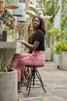 Zwei junge Frauen sitzen im Innenhof eines Restaurants und trinken Weißwein - VEGF00160
