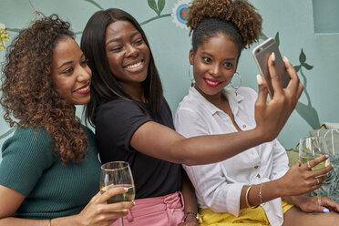 Portrait of three happy friends taking selfie with smartphone - VEGF00168