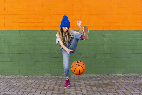 Junges Mädchen spielt Basketball, dribbelt und hebt das Bein - ERRF01229