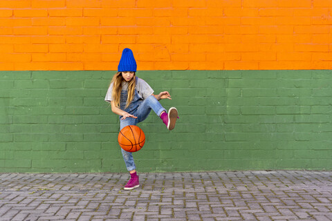 Junges Mädchen spielt Basketball, dribbelt und hebt das Bein, lizenzfreies Stockfoto