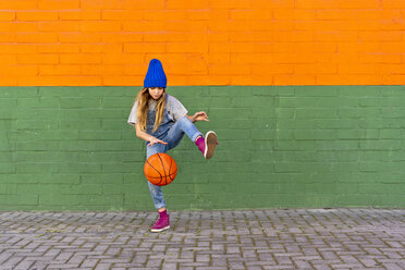 Junges Mädchen spielt Basketball, dribbelt und hebt das Bein - ERRF01230