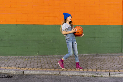 Junges Mädchen spielt Basketball, lachend, lizenzfreies Stockfoto