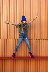 Young girl wearing dungarees, orange wall in the background - ERRF01257