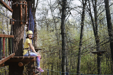 Young woman sitting on a platform in a rope course - EYAF00201