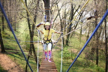Young woman wearing yellow t-shirt and helmet in a rope course - EYAF00209