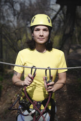 Junge Frau mit gelbem T-Shirt und Helm in einem Hochseilgarten - EYAF00212