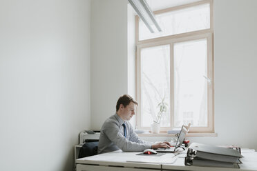 Young businessman using laptop at desk in office - AHSF00293