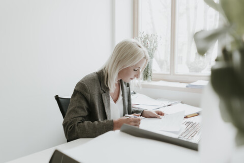 Junge Frau arbeitet am Schreibtisch im Büro, lizenzfreies Stockfoto