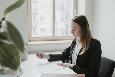 Junge Frau arbeitet am Schreibtisch im Büro - AHSF00304