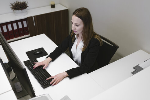 Junge Frau arbeitet an der Rezeption im Büro - AHSF00319