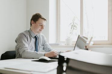 Young businessman using laptop at desk in office - AHSF00326