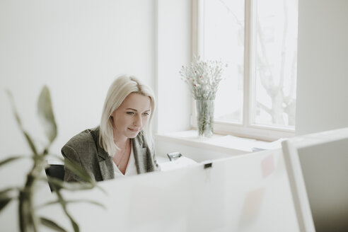 Junge Frau arbeitet am Schreibtisch im Büro - AHSF00329