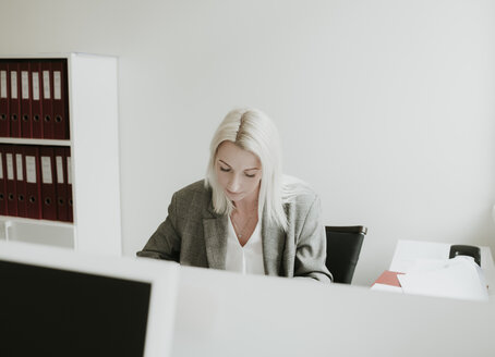 Junge Frau arbeitet am Schreibtisch im Büro - AHSF00330