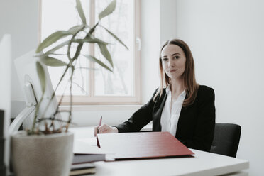 Porträt einer selbstbewussten jungen Frau, die am Schreibtisch im Büro arbeitet - AHSF00337