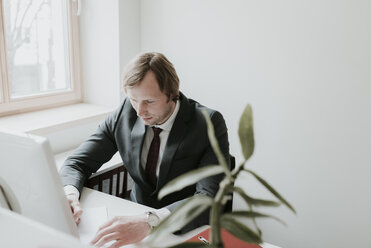 Geschäftsmann mit Computer am Schreibtisch im Büro - AHSF00343