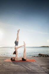 Frauen üben Acro-Yoga am Meer - CUF50664