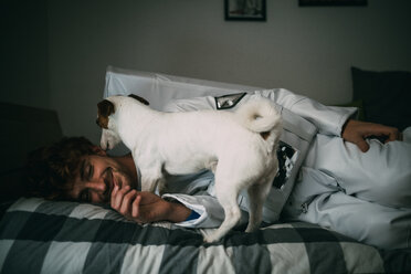 Pet dog licking astronaut on bed - CUF50695