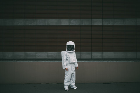 Astronaut steht vor gestreifter Betonwand, lizenzfreies Stockfoto